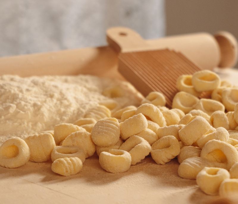 Gnocchi con l'attrezzo di legno per rigarli, farina e mattarello