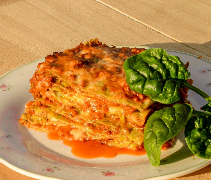 Lasagne verdi al ragù nel piatto, con foglie di spinaci