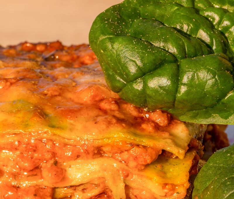 Lasagne verdi al ragù da vicino, con foglie di spinaci