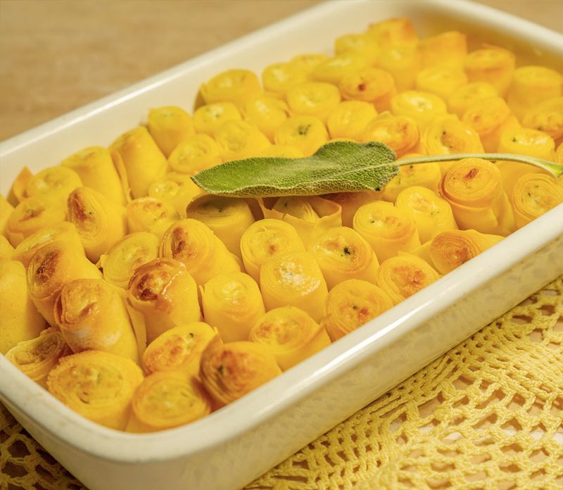 Teglia di panzerotti dorati al forno, con una foglia di salvia