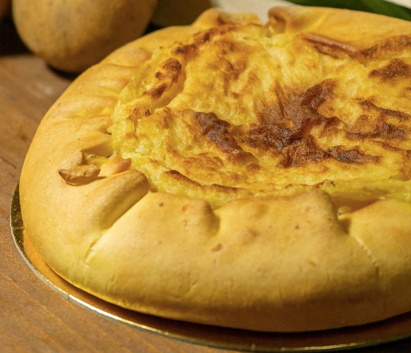 Torta di patate dorata, con le patate sullo sfondo